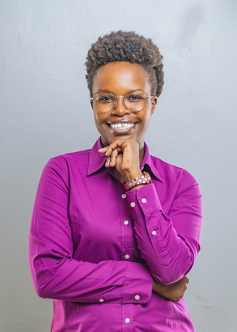 Studio portrait of Naomy Kemei, smiling, in a magenta shirt